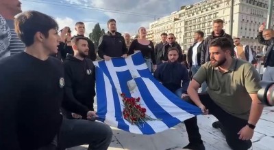 Διαδηλωτές ψέλνουν τον Εθνικό Ύμνο μπροστά από το μνημείο για τα θύματα των Τεμπών στο Σύνταγμα